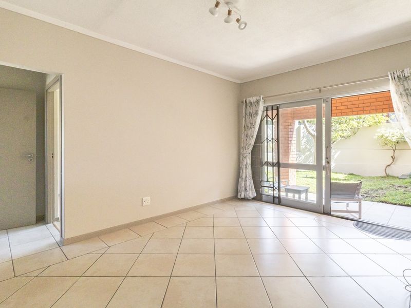 Bright and spacious living area featuring neutral tiled flooring and a large sliding glass door providing direct access to the private garden patio.