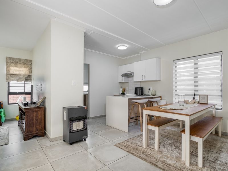 Open-plan living and dining area featuring tiled flooring, a modern kitchen with white cabinetry, and a functional island bench.