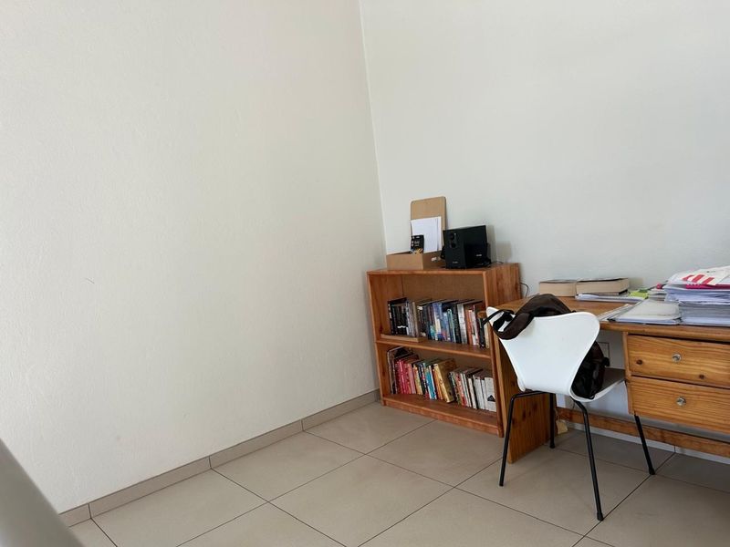 A functional office space featuring neutral tiled flooring and clean wall finishes, suitable for a home workspace or study area.