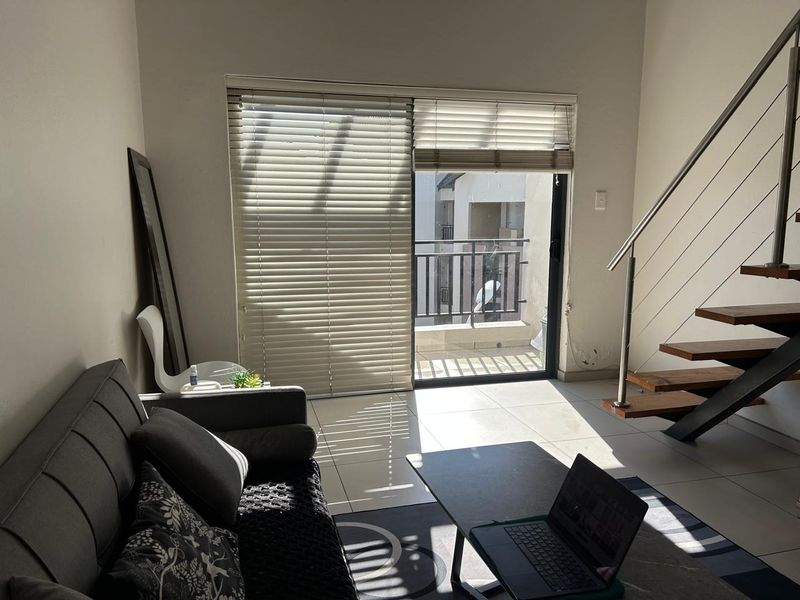 Living room featuring tiled flooring, a modern staircase with metal railings, and a sliding glass door providing access to a balcony.