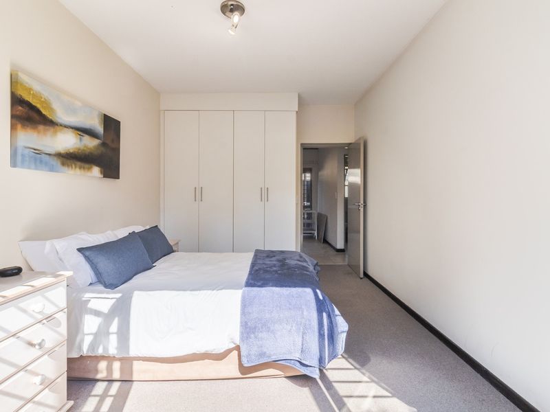 A well-maintained bedroom featuring neutral walls, carpeted flooring, and ample built-in cupboard storage space.