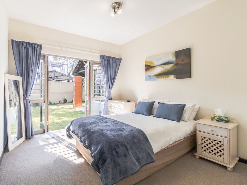A bright bedroom featuring carpeted flooring and a sliding glass door providing direct access to the rear garden area.