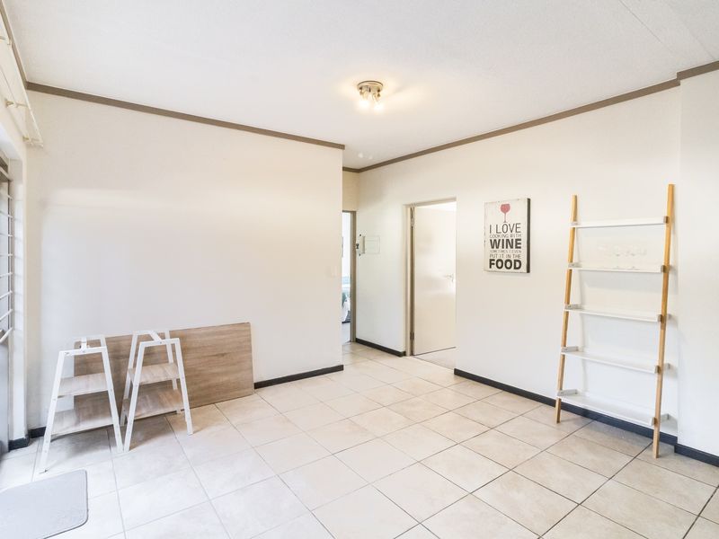 A bright, open-plan living area featuring neutral tiled flooring and a sliding glass door leading to the exterior.