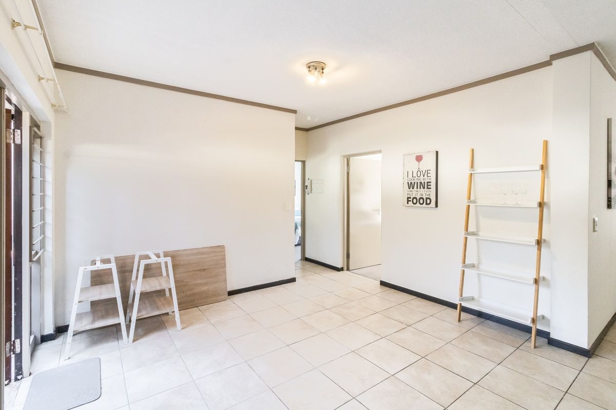 A bright, open-plan living area featuring neutral tiled flooring and a sliding glass door leading to the exterior.