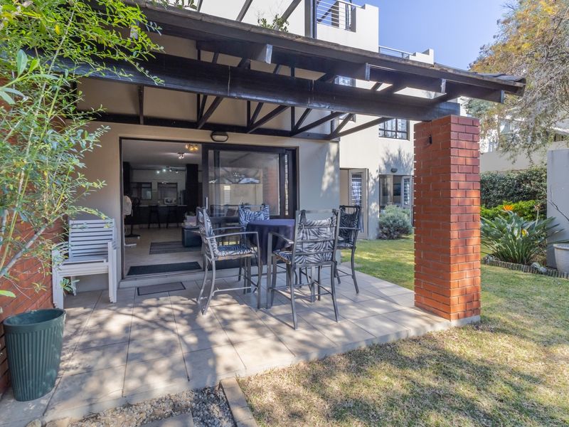A covered patio area featuring a timber pergola, exposed brick pillar, and tiled flooring, providing seamless access to the garden and interior living space.