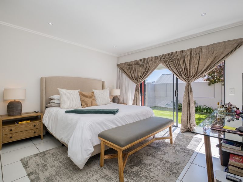 Spacious bedroom featuring tiled flooring, recessed downlights, and a large sliding glass door providing direct access to the garden area.