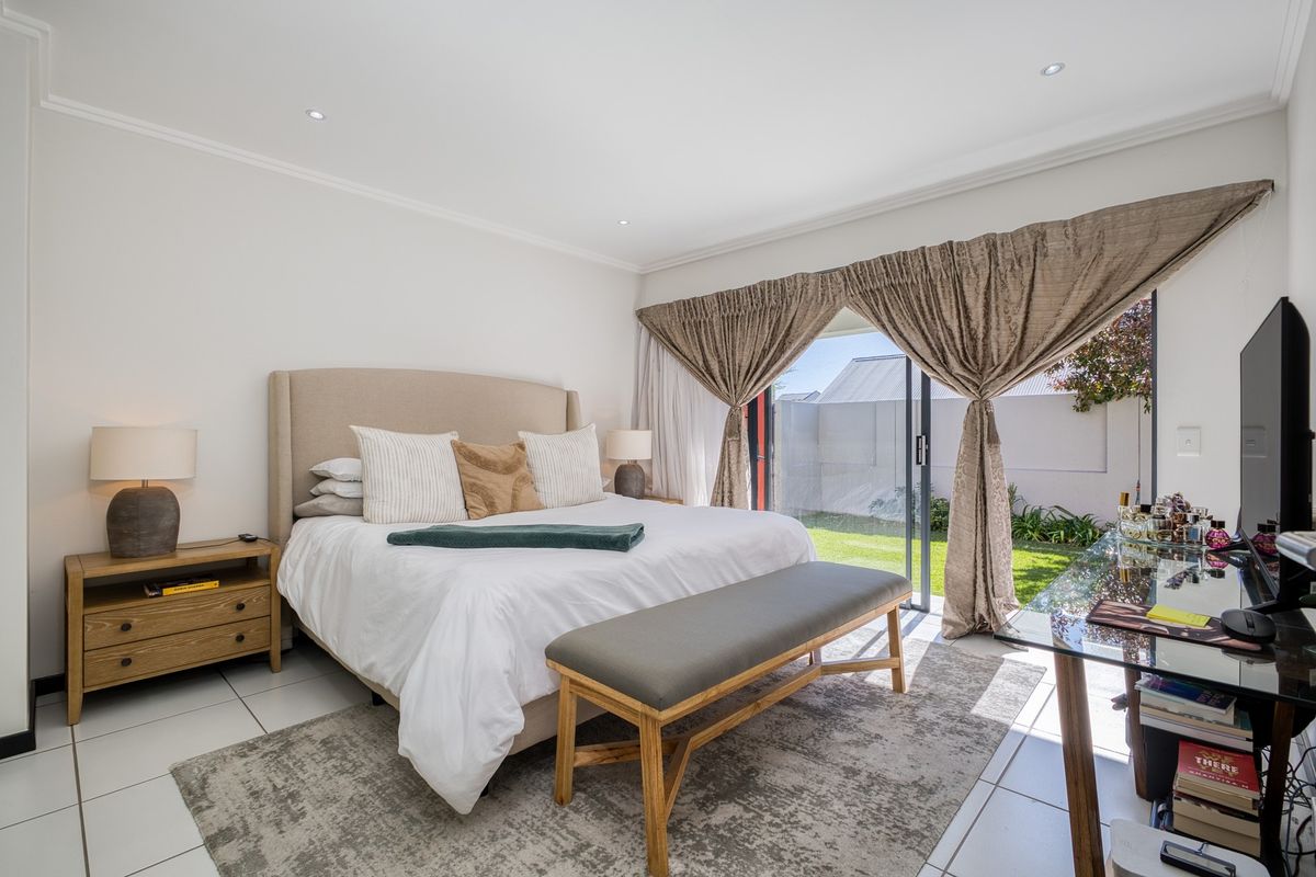 Spacious bedroom featuring tiled flooring, recessed downlights, and a large sliding glass door providing direct access to the garden area.