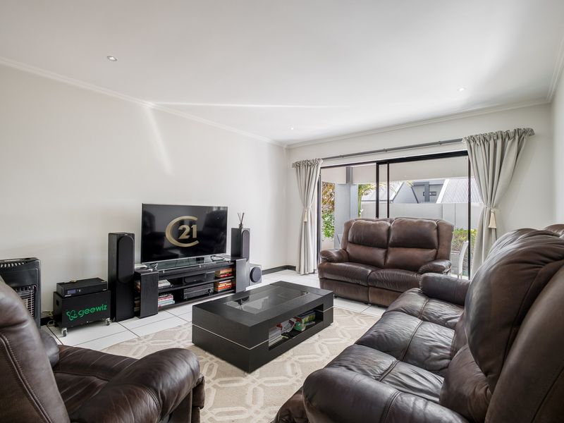 Spacious living room featuring tiled flooring, recessed downlights, and large sliding glass doors providing direct access to the outdoor patio area.