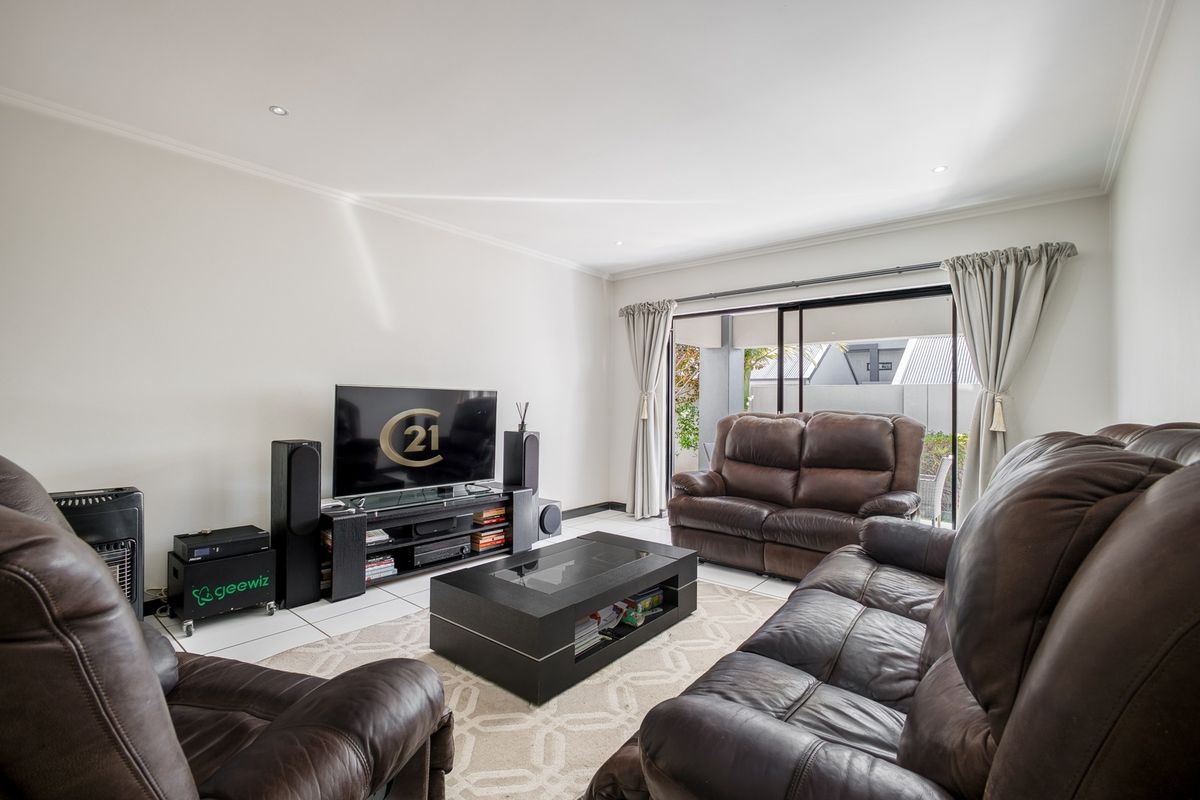 Spacious living room featuring tiled flooring, recessed downlights, and large sliding glass doors providing direct access to the outdoor patio area.