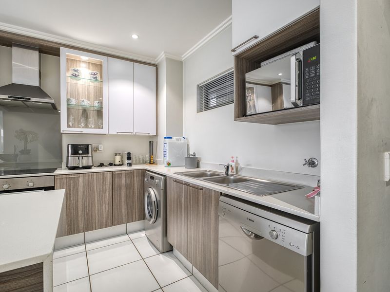 Modern kitchen featuring sleek wood-grain cabinetry, stone countertops, integrated appliances, and high-quality finishes, offering a functional and contemporary cooking space.