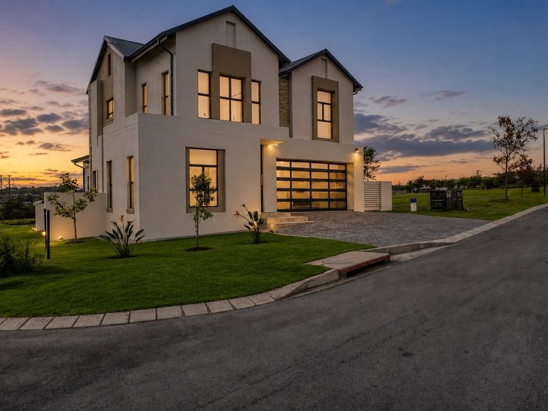 A modern double-story residential property featuring a paved driveway, integrated garage, and well-maintained landscaped garden at dusk.
