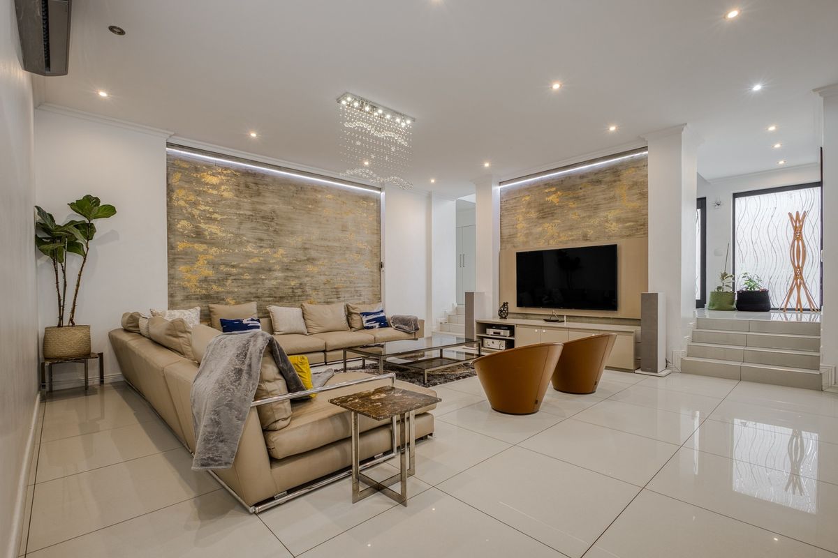 Spacious modern living room featuring high-gloss porcelain tiles, recessed downlighting, and elegant metallic feature walls with integrated media cabinetry.