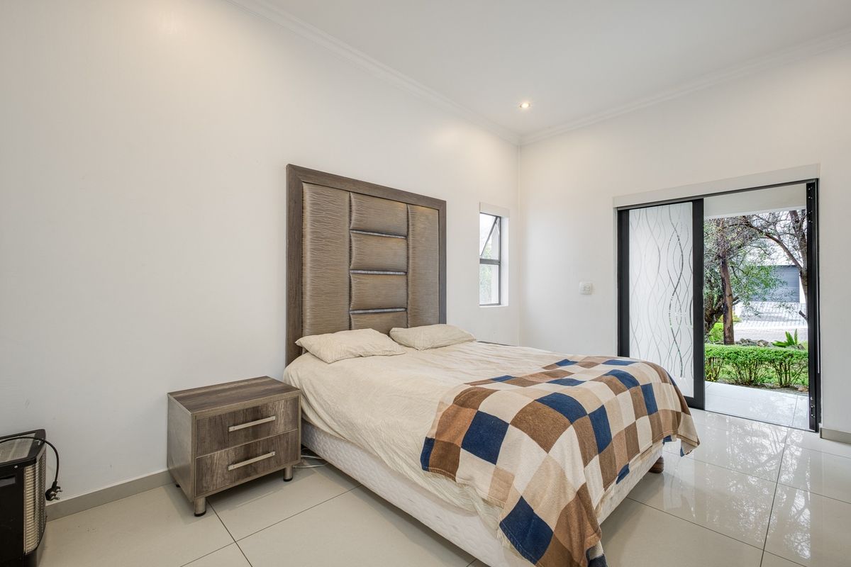 A bright bedroom featuring tiled flooring, recessed lighting, and a sliding glass door providing direct access to the garden area.