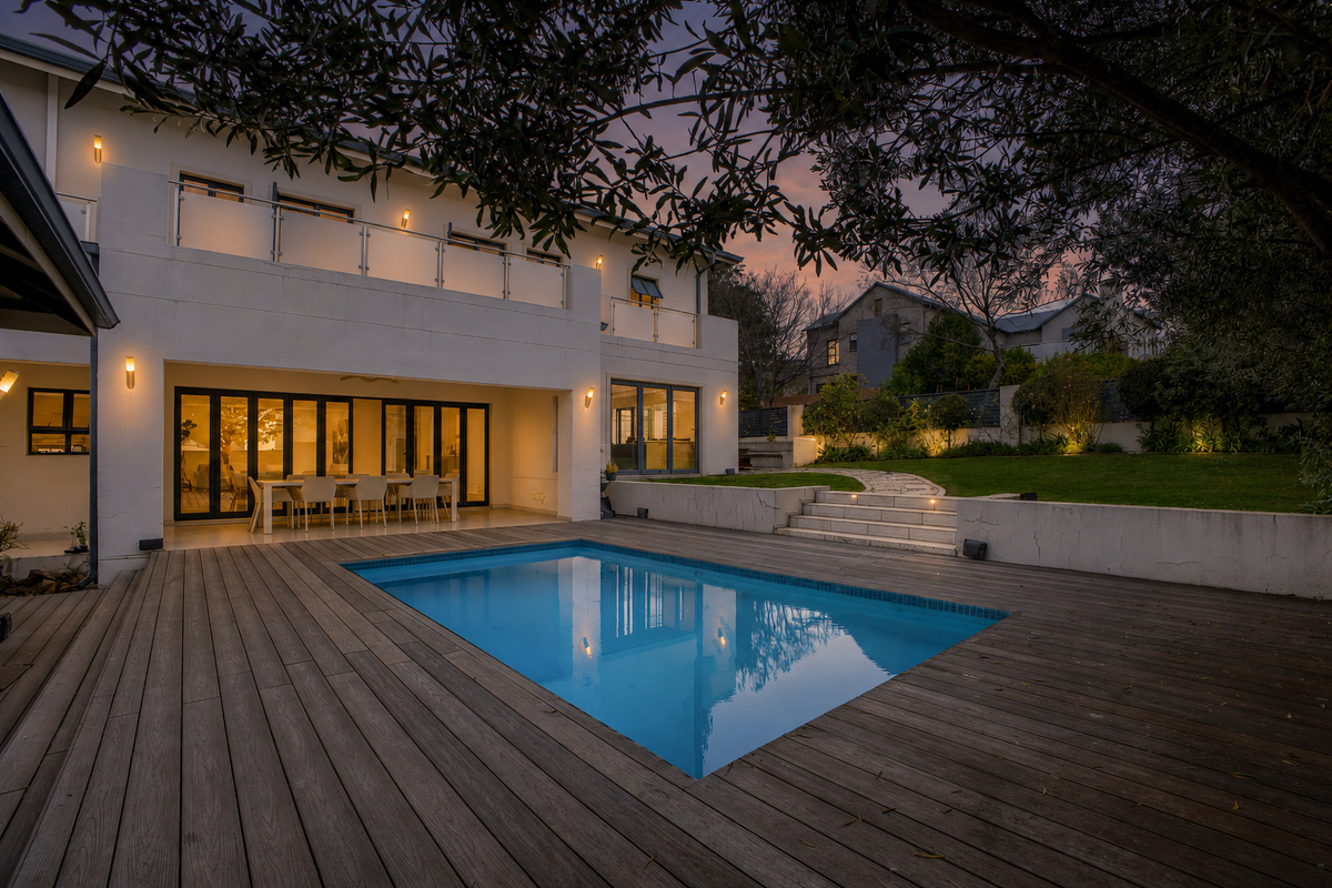 A beautifully landscaped rear exterior featuring a swimming pool, timber decking, and a spacious patio area with bi-fold doors leading into the home.