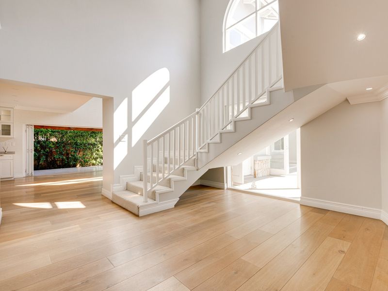 Spacious entrance hall featuring light timber flooring, a grand staircase, and an arched window, providing a bright and welcoming transition to the home.