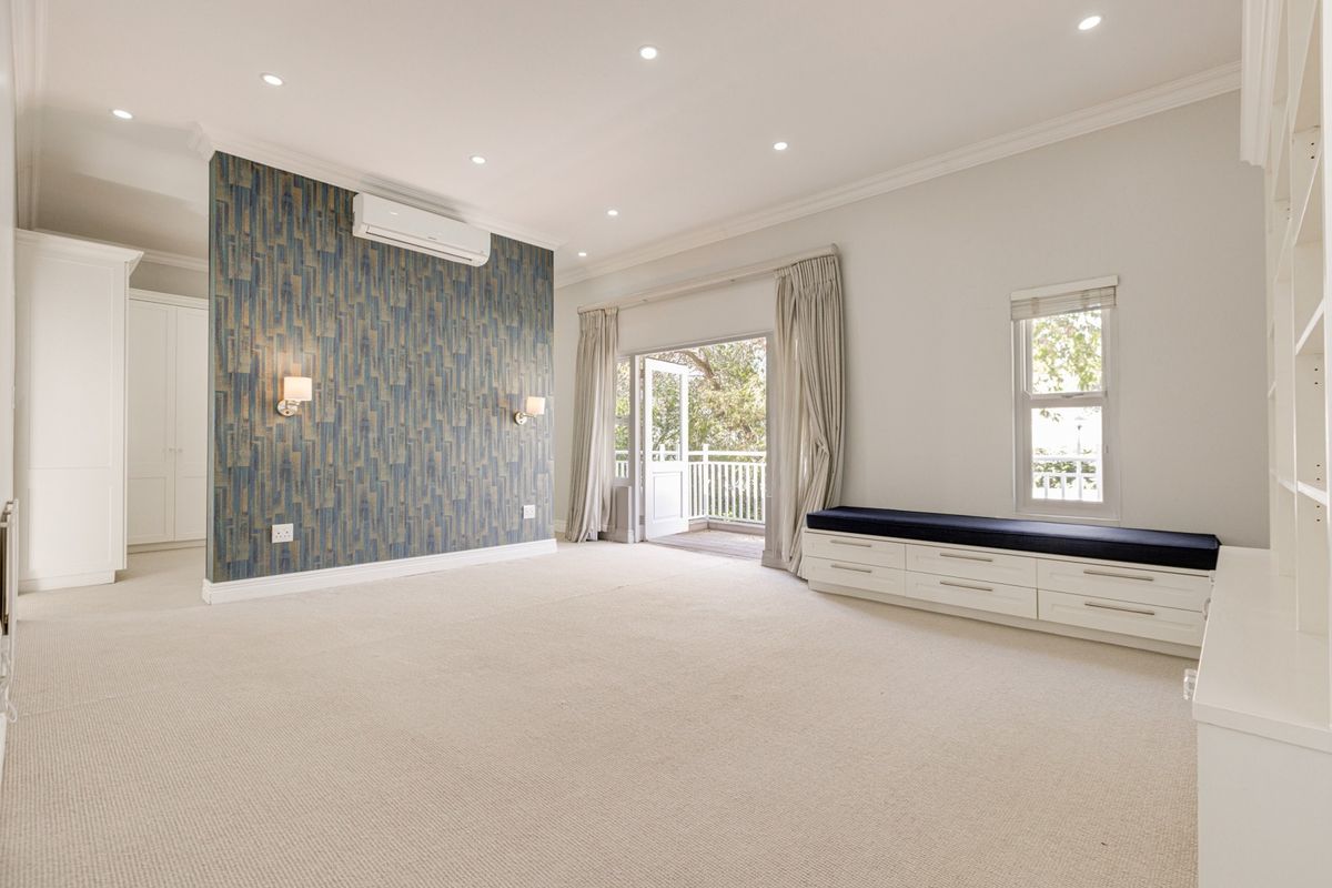 Spacious bedroom featuring neutral carpeting, built-in cabinetry, a window seat, and direct access to a private balcony through French doors.