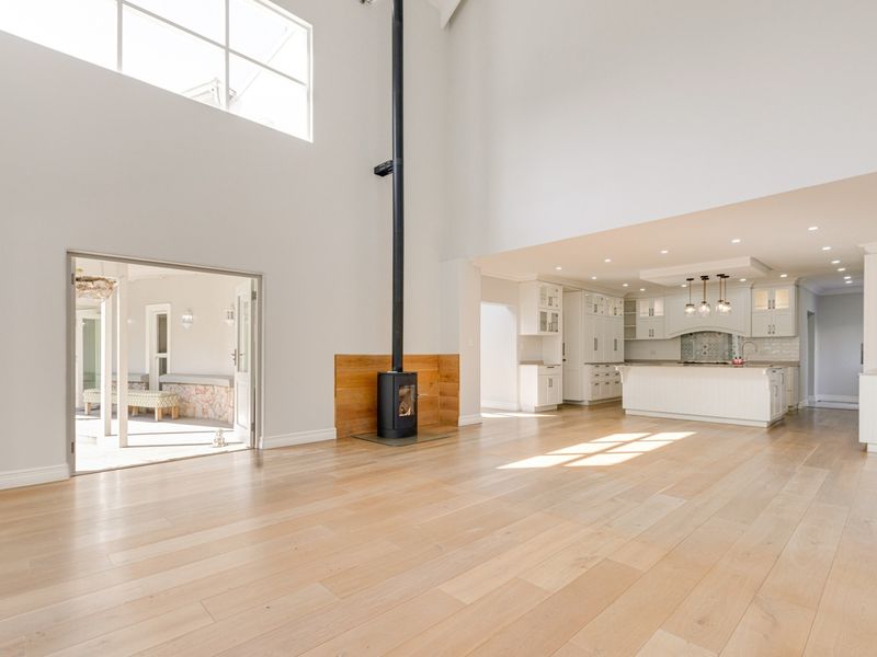 Spacious open-plan living area featuring high ceilings, a modern fireplace, and a sleek kitchen with a central island and ample cabinetry.