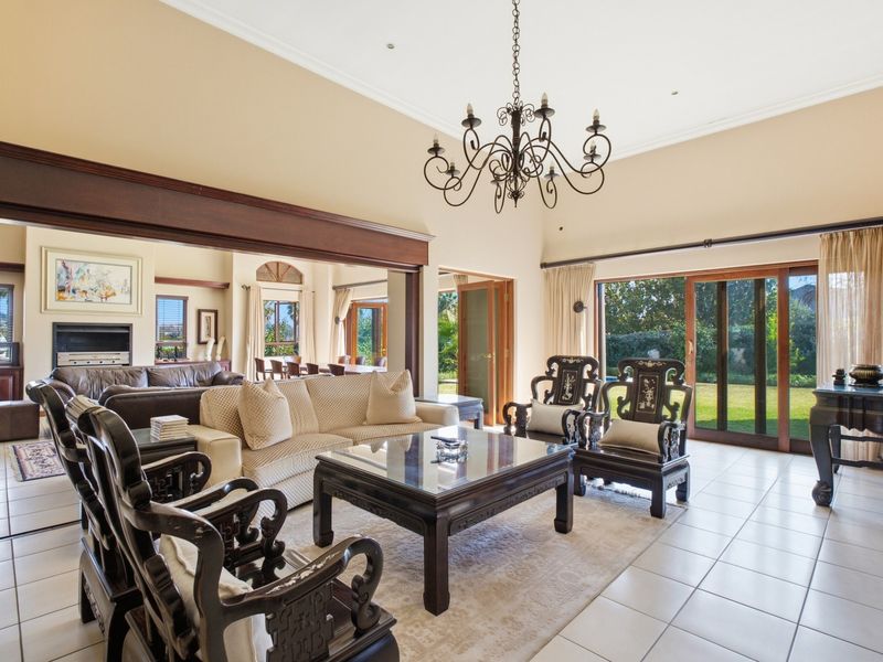 Spacious open-plan living area featuring vaulted ceilings, tiled floors, a built-in fireplace, and large sliding glass doors providing seamless access to the garden.