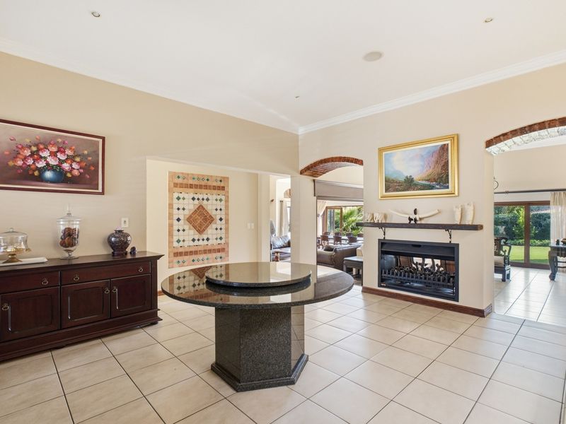 Spacious living area featuring a built-in fireplace, tiled flooring, and elegant brick archways leading to adjacent rooms.