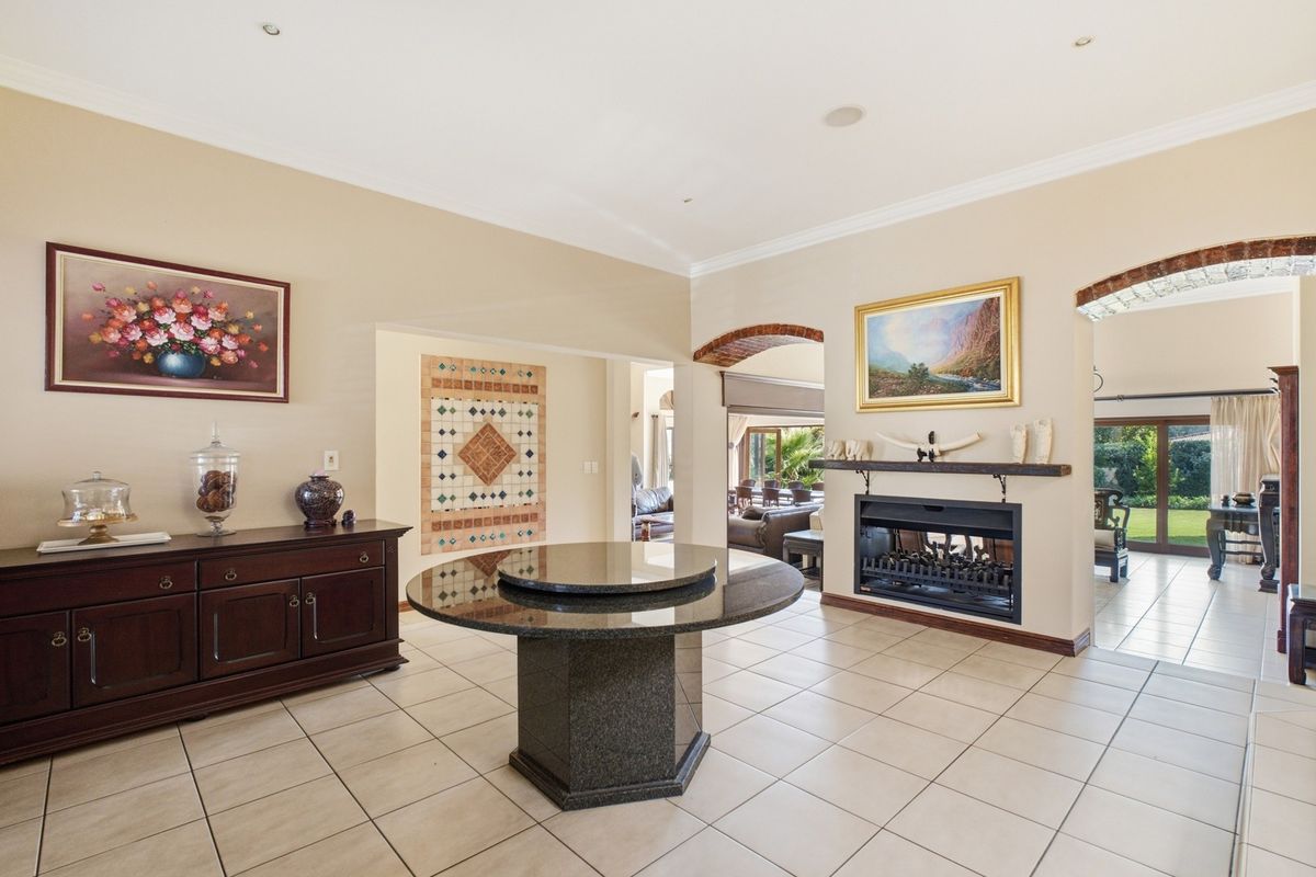 Spacious living area featuring a built-in fireplace, tiled flooring, and elegant brick archways leading to adjacent rooms.