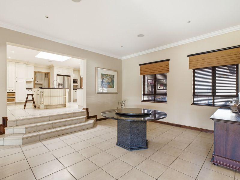 Spacious open-plan living and dining area featuring tiled floors, recessed lighting, and a raised kitchen with built-in cabinetry and a central island.
