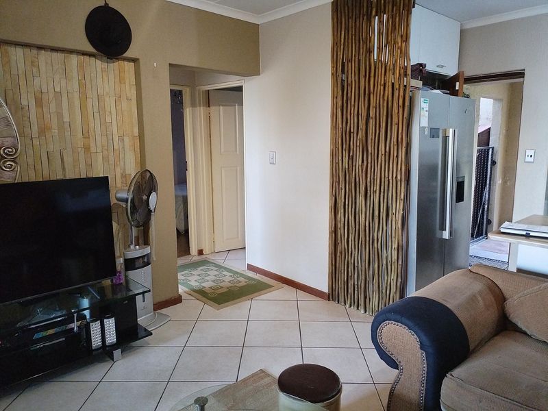 Open plan living area featuring tiled flooring and a decorative stone feature wall, providing access to adjacent rooms.