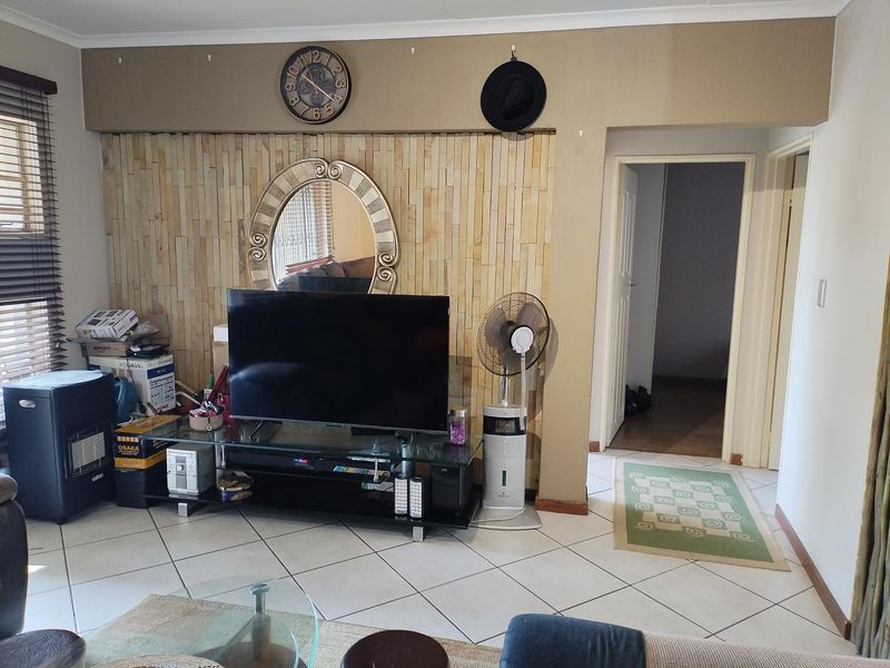Living room featuring a stone accent wall and tiled flooring, providing a neutral base for potential interior updates.