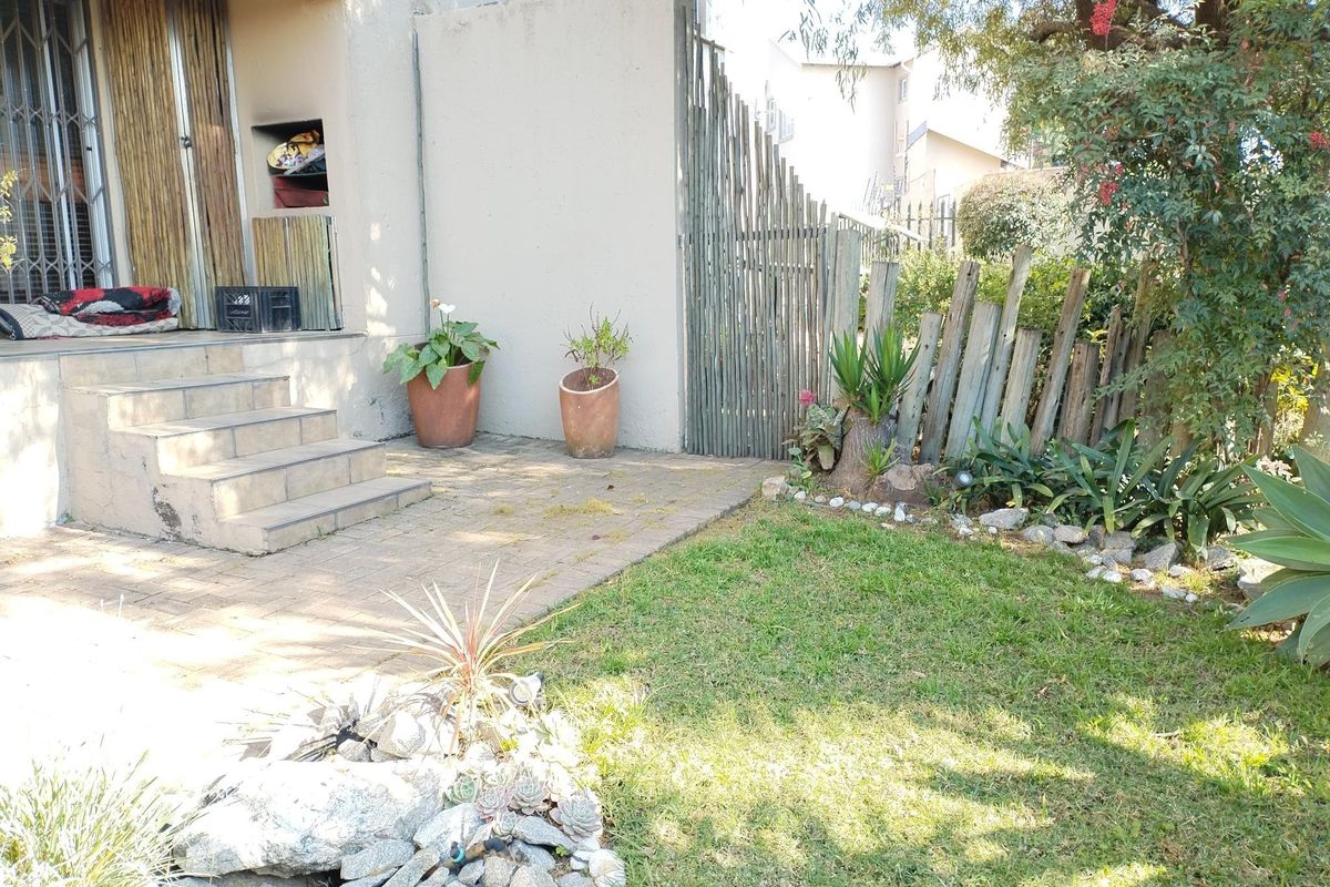A private rear garden featuring a paved patio area, tiled steps leading to the entrance, and established landscaping with timber fencing.