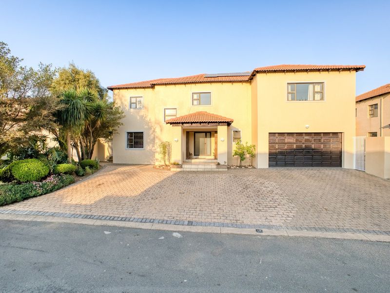 A well-maintained double-story residential home featuring a paved driveway, double garage, and tiled roof, set within a landscaped front garden.
