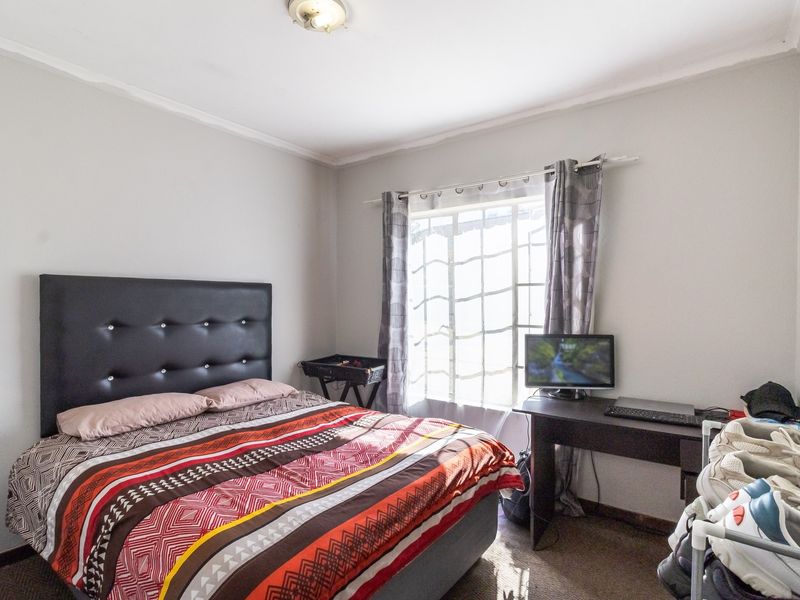 A functional bedroom featuring a window with natural light and a standard ceiling light fixture.