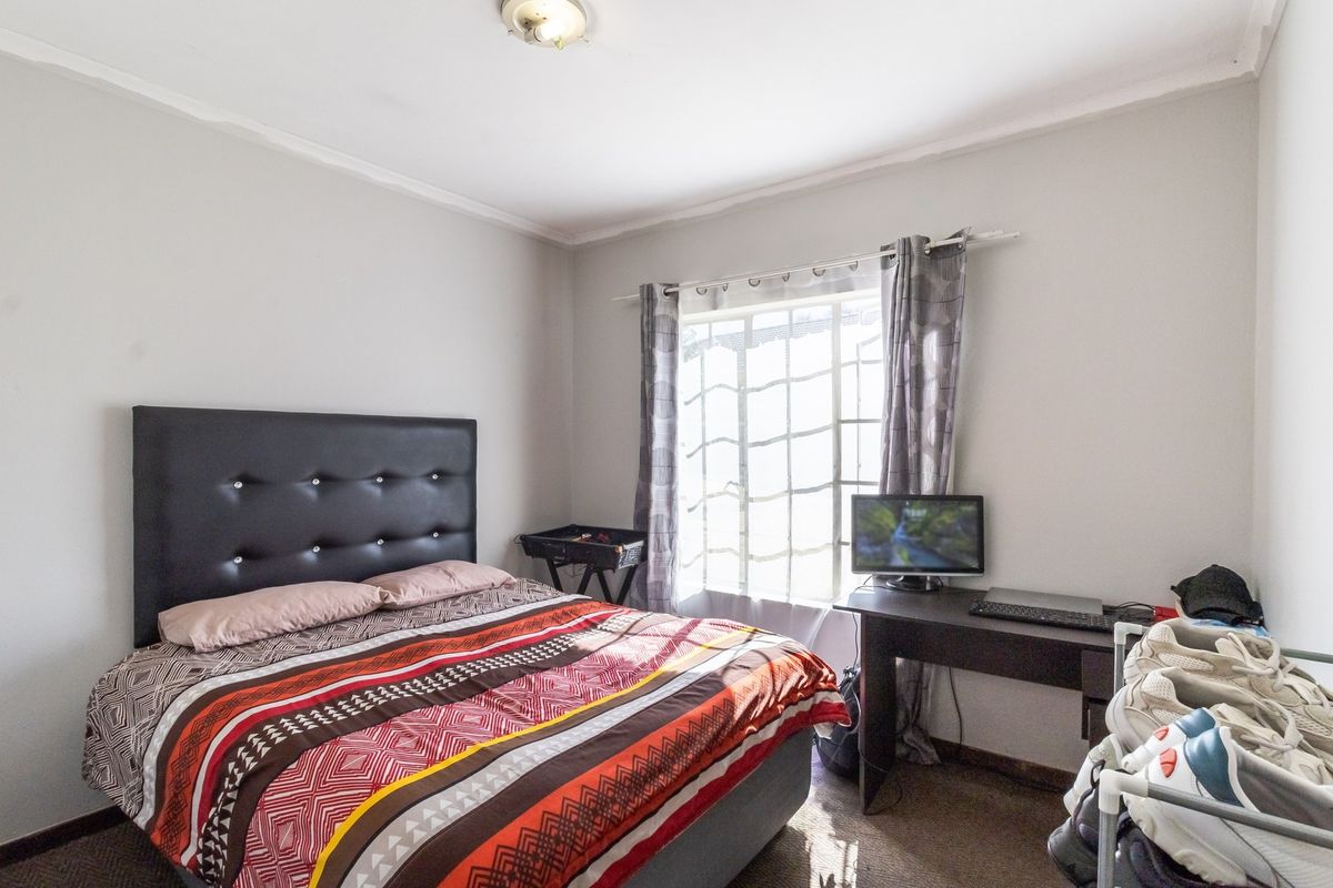 A functional bedroom featuring a window with natural light and a standard ceiling light fixture.