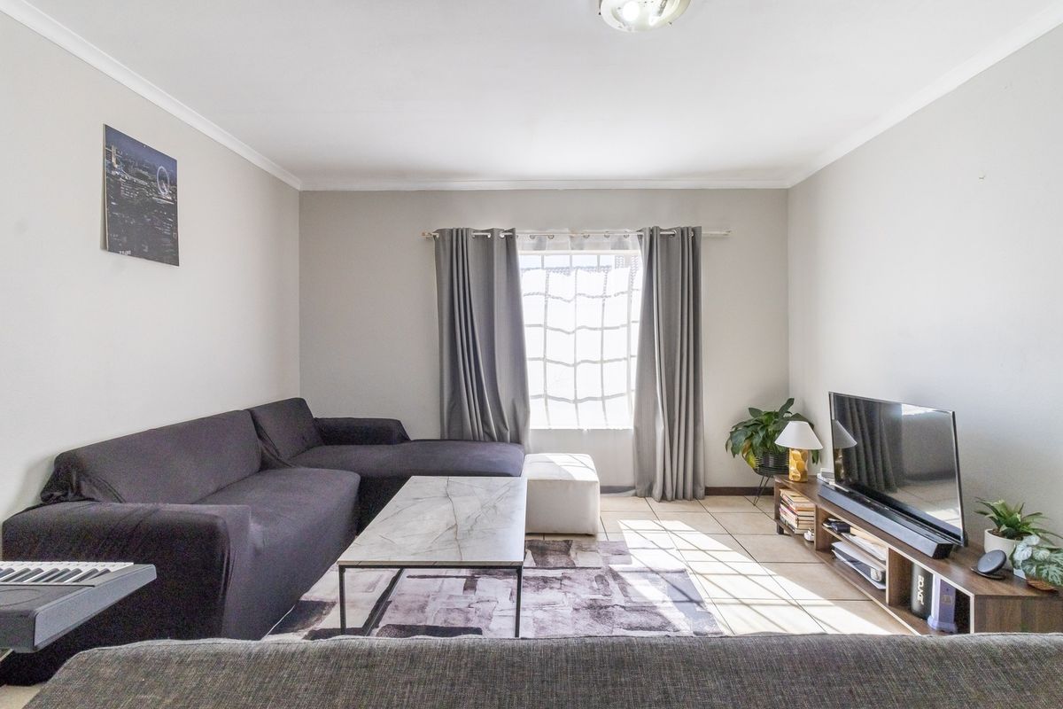 A well-lit living room featuring tiled flooring and coved ceilings, providing a comfortable and functional space for relaxation.