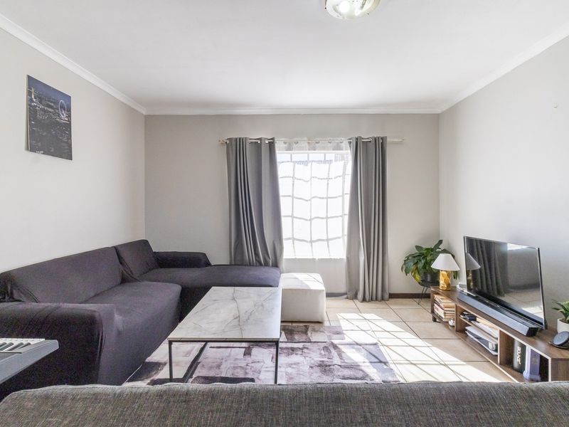 A well-lit living room featuring tiled flooring and coved ceilings, providing a comfortable and functional space for relaxation.