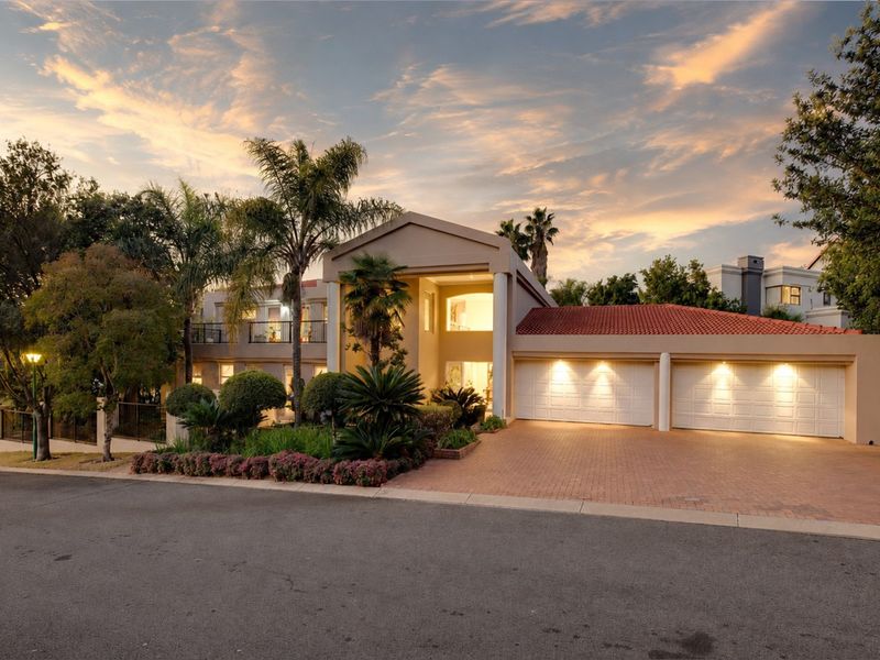 A well-maintained double-story residence featuring a paved driveway, double garage, and an attractive landscaped front garden under a sunset sky.