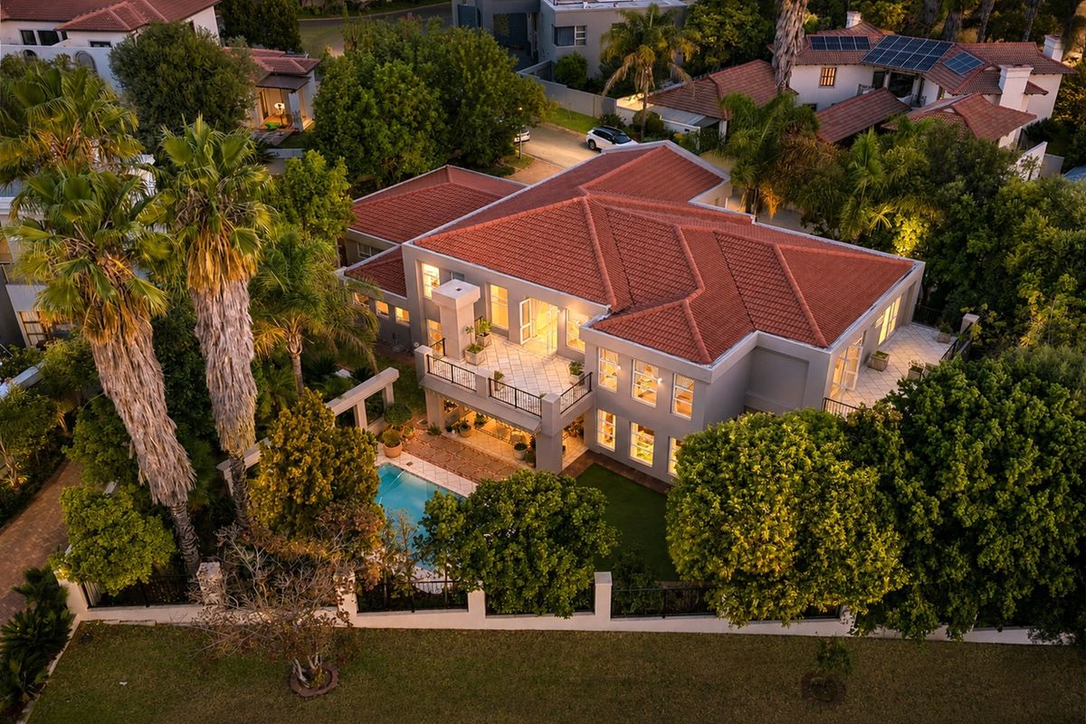 Aerial view of a large residential property featuring a tiled roof, swimming pool, spacious balcony, and well-maintained landscaped gardens.