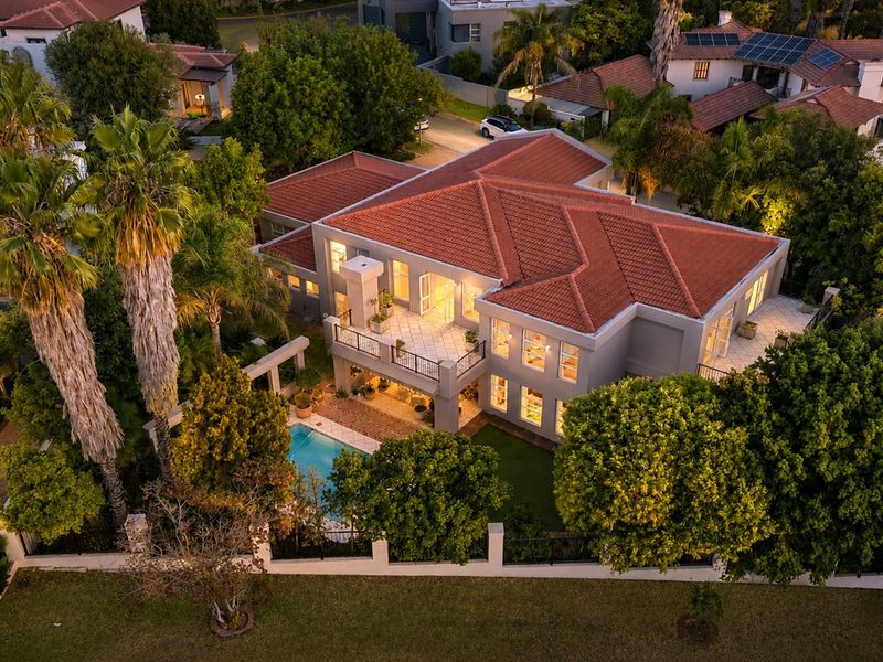 Aerial view of a large residential property featuring a tiled roof, swimming pool, spacious balcony, and well-maintained landscaped gardens.