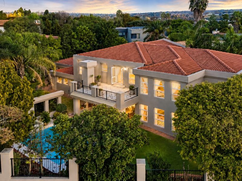 Aerial view of a large multi-story residence featuring a terracotta tile roof, a private swimming pool, and a spacious upper-level balcony.