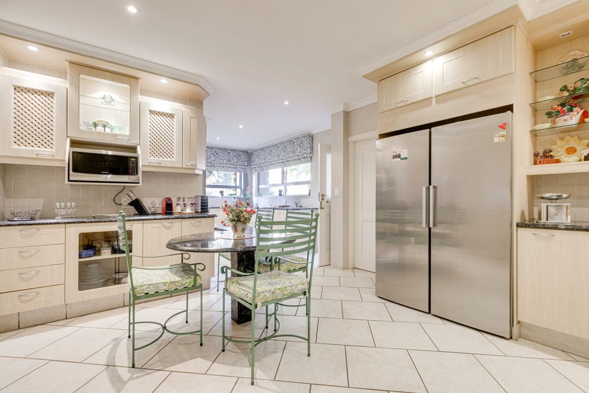 A well-maintained kitchen featuring light wood cabinetry, granite countertops, tiled flooring, and integrated appliances, offering a functional and bright cooking and dining space.