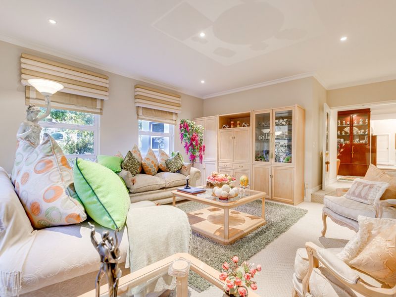 A well-maintained living room featuring neutral carpeting, recessed downlighting, and custom built-in cabinetry, offering a comfortable and functional space.