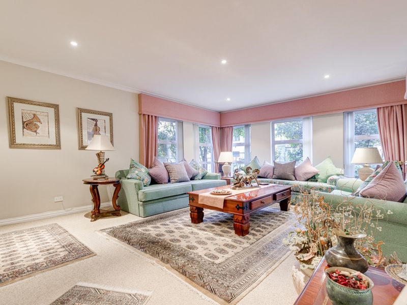 A spacious and well-lit living room featuring large windows with custom pelmets and recessed downlighting, offering a comfortable and inviting atmosphere.