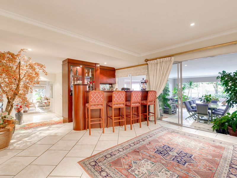 Spacious living area featuring a built-in wooden bar with cabinetry, tiled flooring, and large sliding glass doors providing seamless access to the outdoor patio.