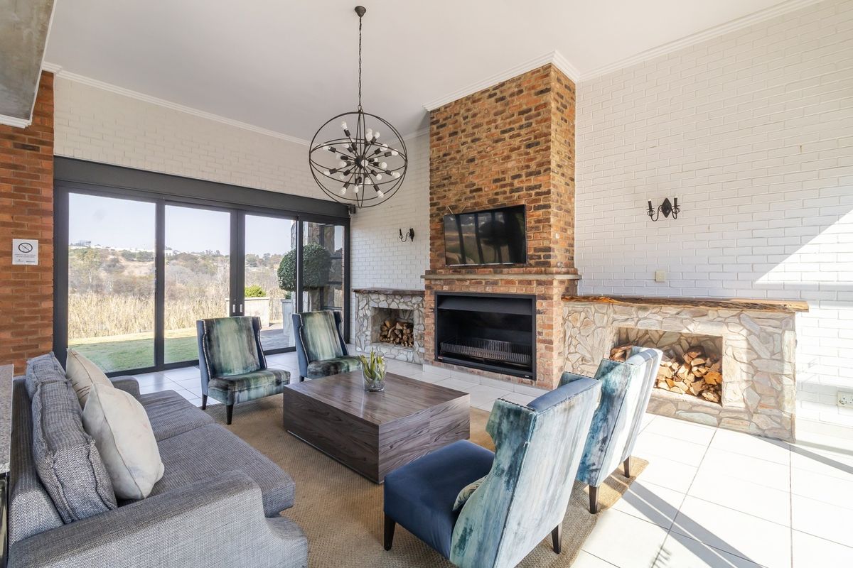 Spacious living room featuring a prominent brick fireplace with stone hearth, large sliding glass doors, and tiled flooring with views of the exterior.