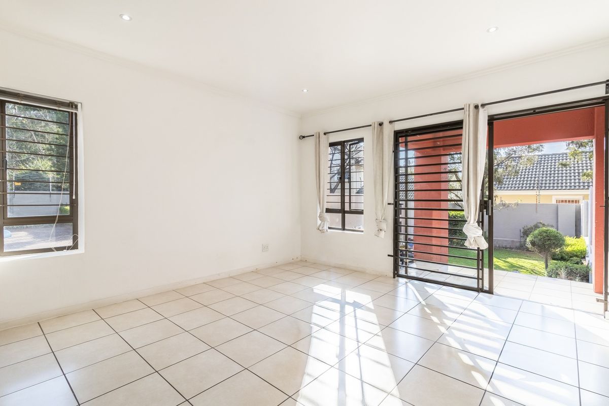 Bright and spacious living area featuring neutral tiled flooring, recessed lighting, and large sliding doors providing direct access to the outdoor patio and garden.
