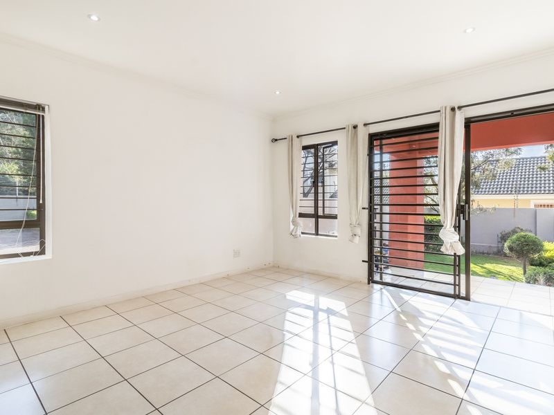 Bright and spacious living area featuring neutral tiled flooring, recessed lighting, and large sliding doors providing direct access to the outdoor patio and garden.