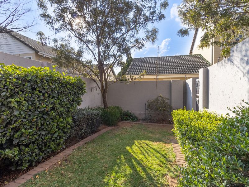 A private, well-maintained garden area featuring a neat lawn, established hedges, and secure perimeter walling.