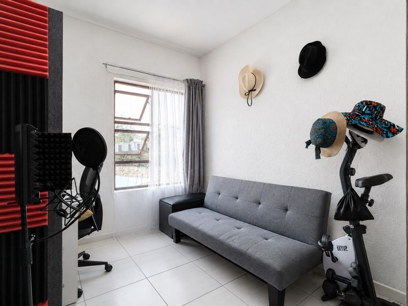 A compact bedroom featuring tiled flooring and a casement window, currently utilized as a multi-purpose hobby and exercise space.