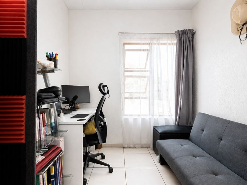 A compact home office space featuring tiled flooring and a window, suitable for a dedicated workspace or study area.