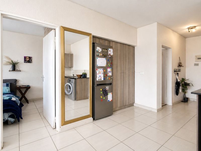 Open plan living area featuring tiled flooring and built-in cabinetry, with direct access to an adjacent bedroom and laundry area.