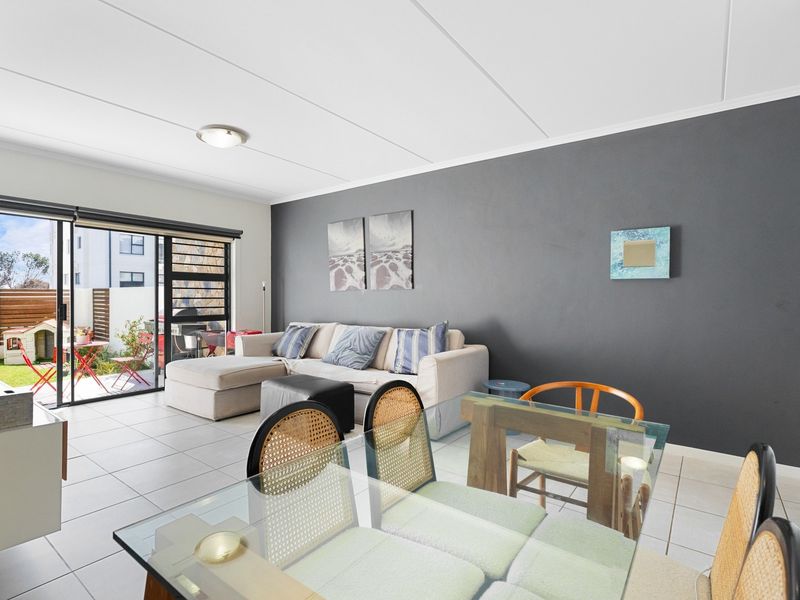 Open plan living and dining area featuring tiled flooring and large sliding glass doors providing direct access to the outdoor patio space.