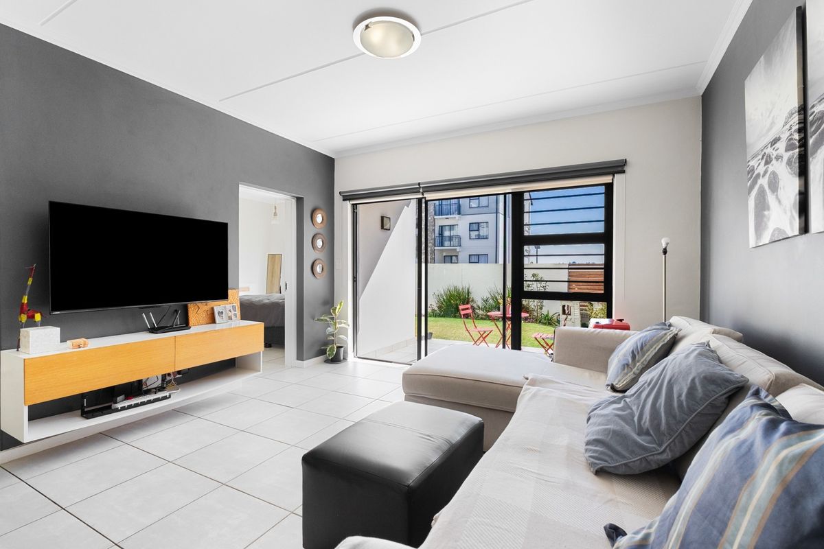 Bright living room featuring tiled flooring and large sliding glass doors providing direct access to the outdoor patio area.